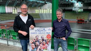 Uwe Dieterich (links) und Claus Regelmann präsentieren das Plakat des European Darts Grand Prix. Am Wochenende platzt der Glaspalast aus allen Nähten. Bild: Holzapfel